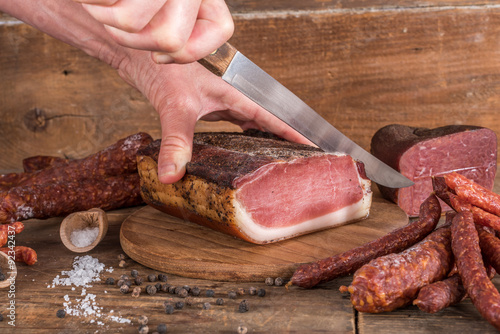 Hand cutting a slice of smoked loin bacon