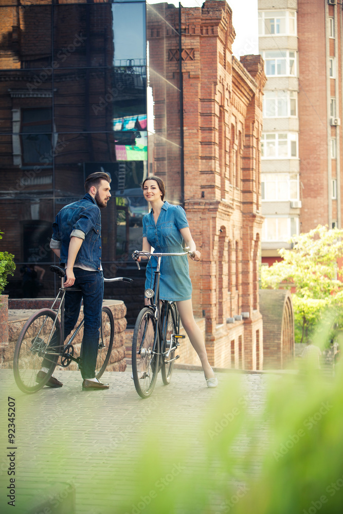 Obraz premium Young couple sitting on a bicycle opposite the city