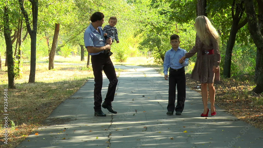 Family walking on the avenue in the park on a sunny day Family walking on the avenue in the park on a sunny day