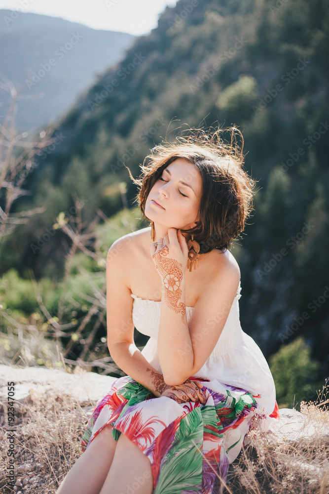 Young beautiful woman in a modern dress with mehendi posing among mountains Young beautiful woman in a modern dress with mehendi posing among mountains
