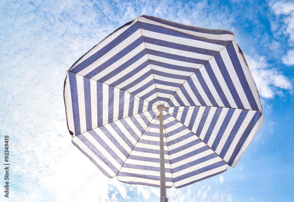 Fototapeta premium Blue and white sun beach umbrella and blue sky with clouds