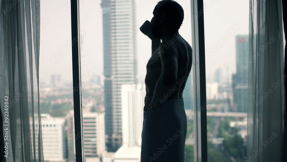 Young man in towel drinking coffee and admire view from window
Young man in towel drinking coffee and admire view from window