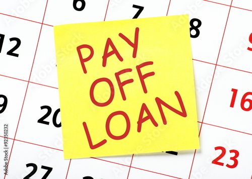 Pay Off Loan message in red text on a yellow sticky note posted on a wall calendar as a reminder photo