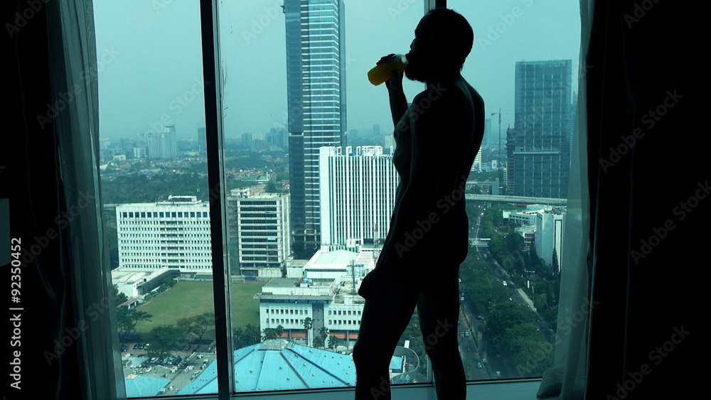 Young man in pants drinking juice and admire view from window
Young man in pants drinking juice and admire view from window