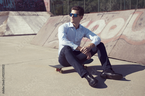Yound caucasian business man relaxing on skateboard .