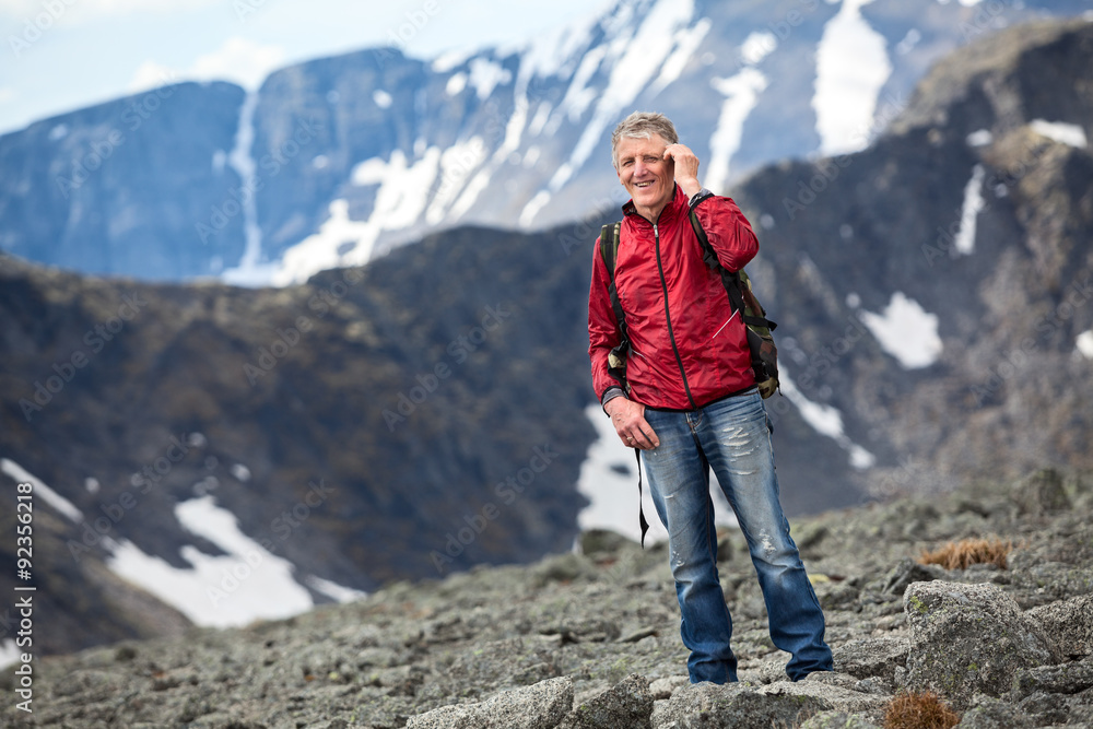 Smiling hiker with a backpack talking on cell phone on the background of the mountains Smiling hiker with a backpack talking on cell phone on the background of the mountains