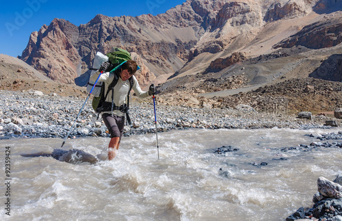 Two hikers crossing mountain river