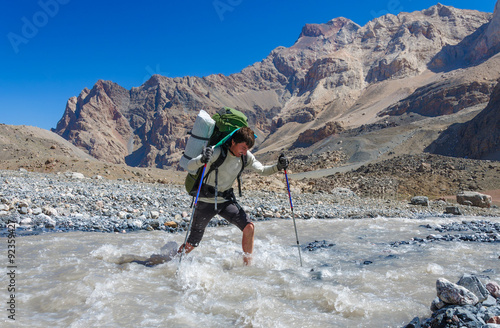 Hiker crossing mountain river