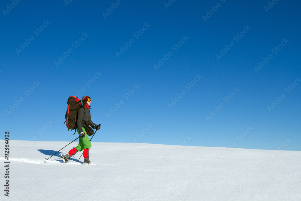 Winter hiking in the mountains on snowshoes with a backpack and tent.