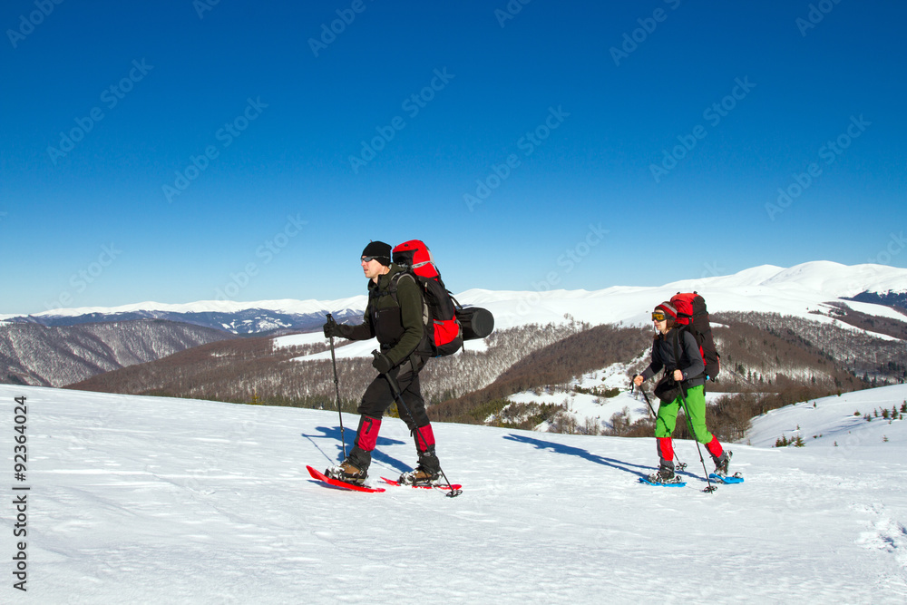 Winter hiking in the mountains on snowshoes with a backpack and tent.