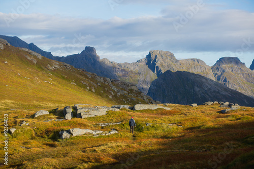 Beautiful Vibrant Norwegian Mountain Landscape from Ryten peak - famous mountain in Lofoten Islands, Moskenes municipality, Nordland with a view of Kvalvika beach, with hiking tourists and blue sky 