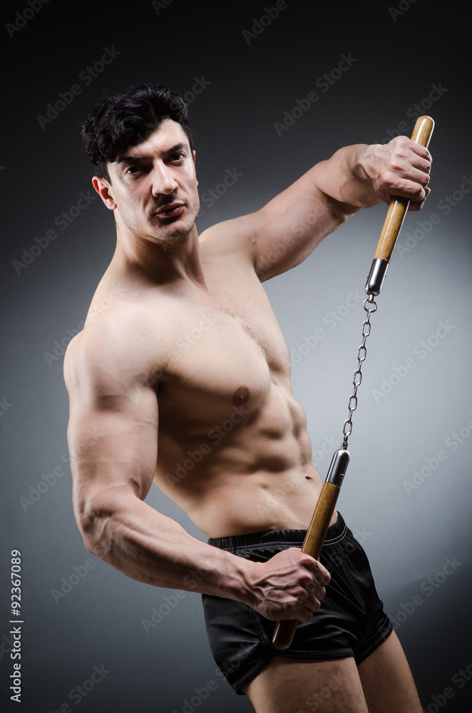 Muscular strong man with nunchucks Muscular strong man with nunchucks