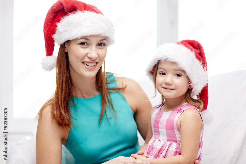 happy mother and little girl in santa hats at home happy mother and little girl in santa hats at home