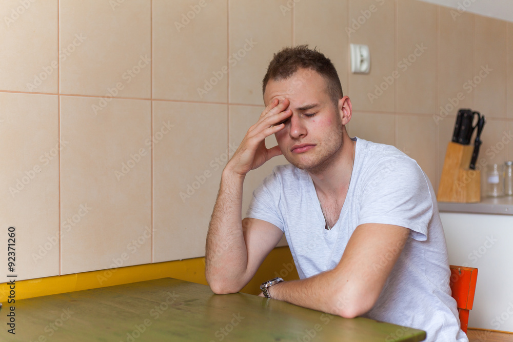 Young man siiting in the kitchen. Monday morning. Hangover. Indoor photo. Young man siiting in the kitchen. Monday morning. Hangover. Indoor photo.
