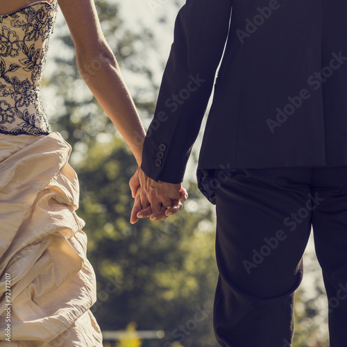 View from behind of newlywed couple holding hands