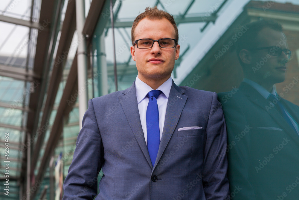 Portrait of young businessman standing in front of office block. Portrait of young businessman standing in front of office block.
