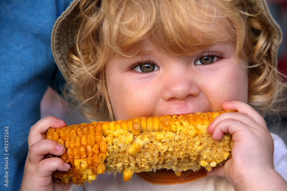 Kleinkind isst gegrillten Maiskolben Stock-Foto | Adobe Stock