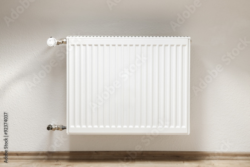 Heating radiator in a white room with laminated wooden floor photo