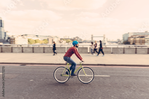 Hipster man cycling on London bridge with fixed gear bike