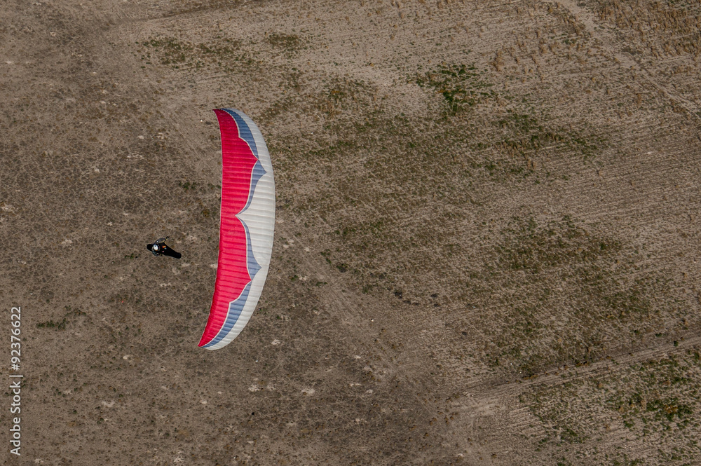 Blue and white paraglider flying over the fields in Turkey, Aksaray Blue and white paraglider flying over the fields in Turkey, Aksaray