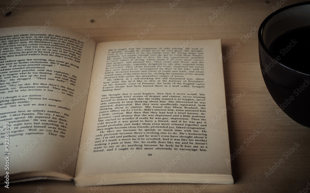 Fototapeta premium reading a book on a wooden table with coffee
