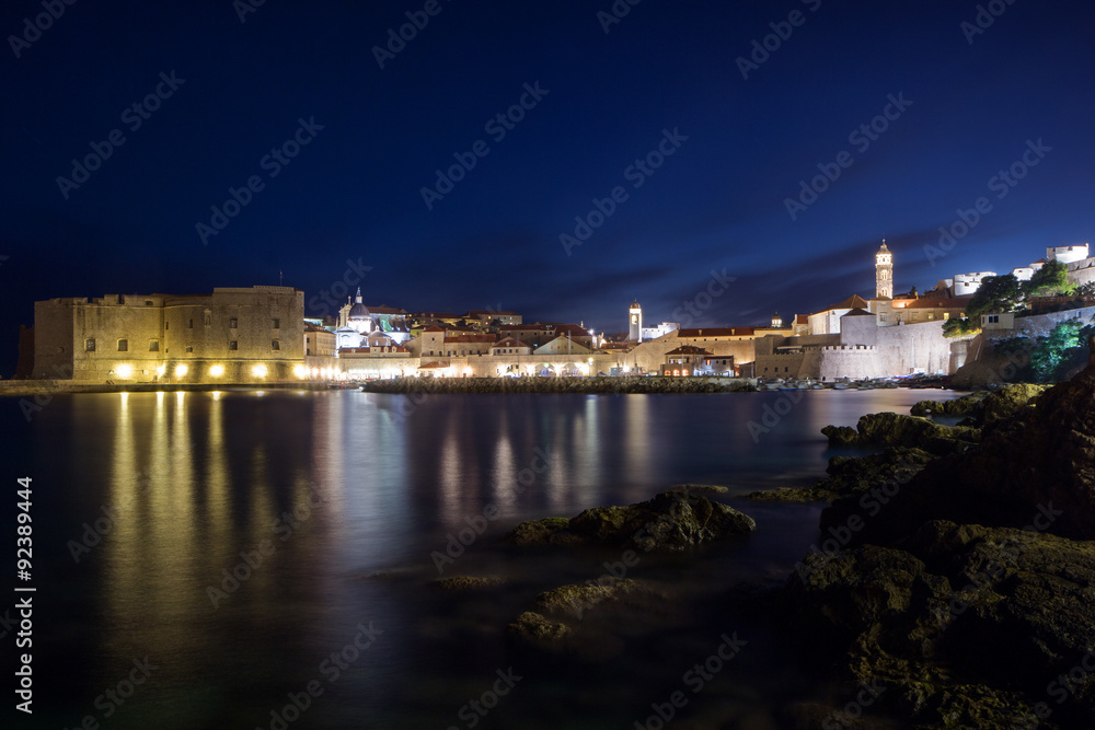 Lit Old Town and rocky coast in Dubrovnik, Croatia at night.