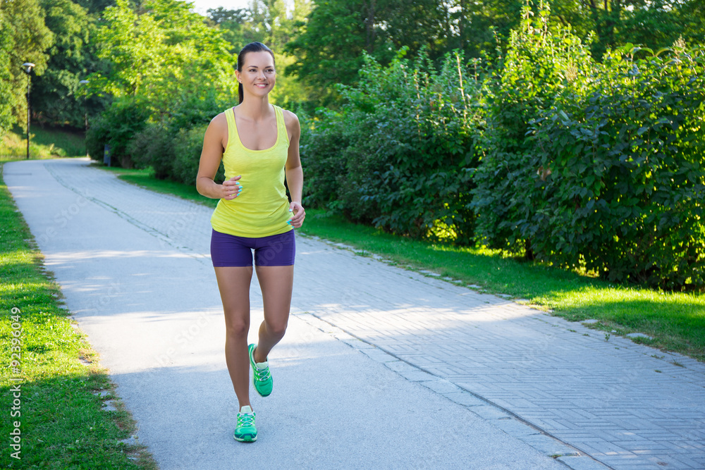 Happy slim jogging woman running in park