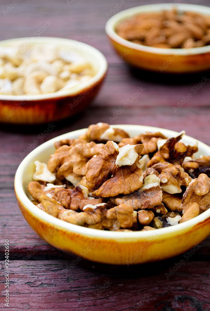 Assorted nuts in dishes on wooden table Assorted nuts in dishes on wooden table