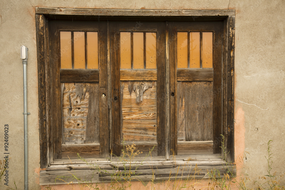 Fototapeta premium Three old brown doors, each with three orange windows, in tan plaster wall, Jackson, Wyoming.