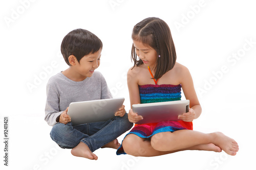 Boy and girl using tablet while sitting on the floor