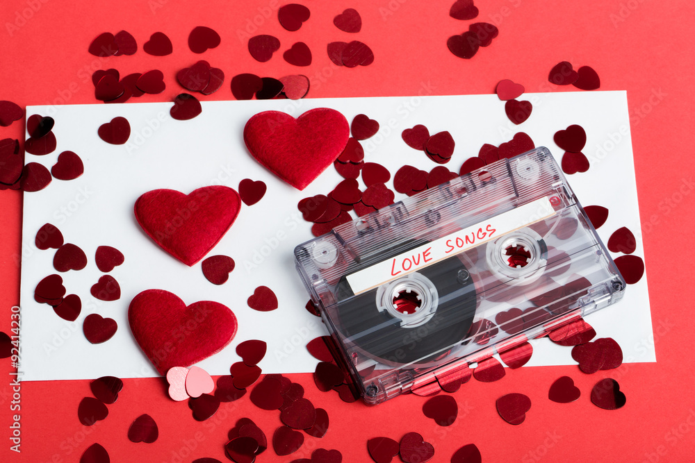 Audio cassette tape on red background with fabric heart