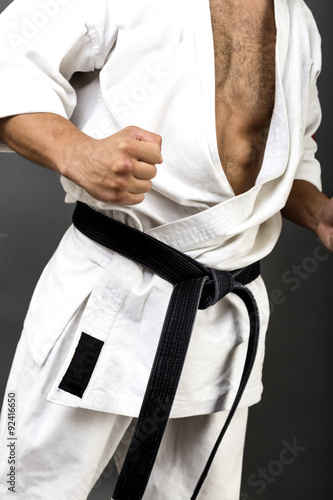 Young man in white kimono and black belt training martial art