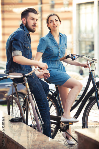 Young couple sitting on a bicycle opposite city 