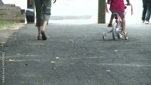 Mother walking along side child on bike with training wheels photo