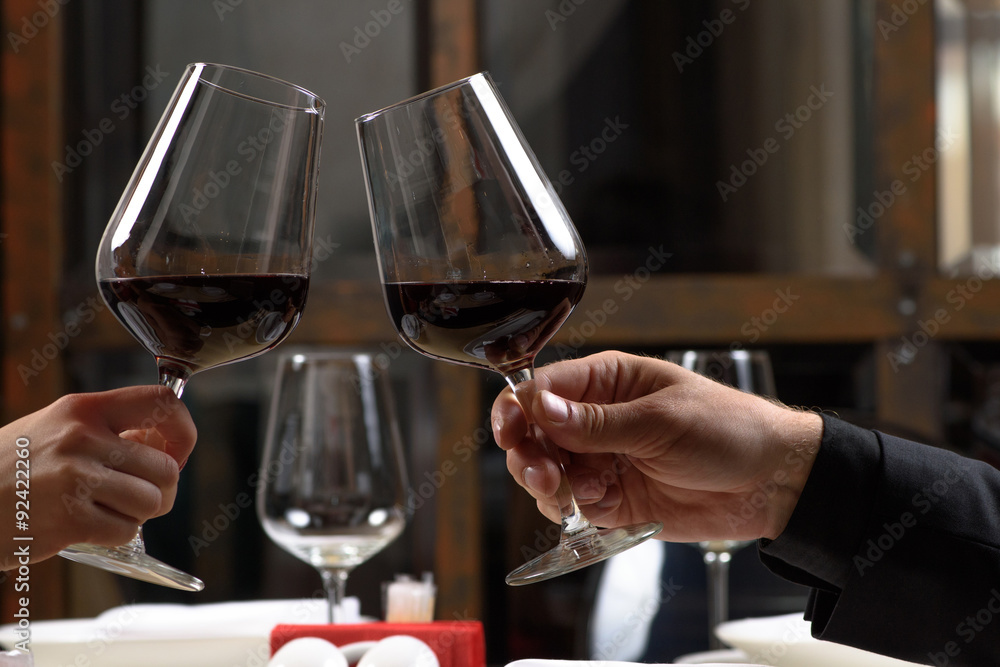 Couple drinking red wine in restaurant. Close-up hands with