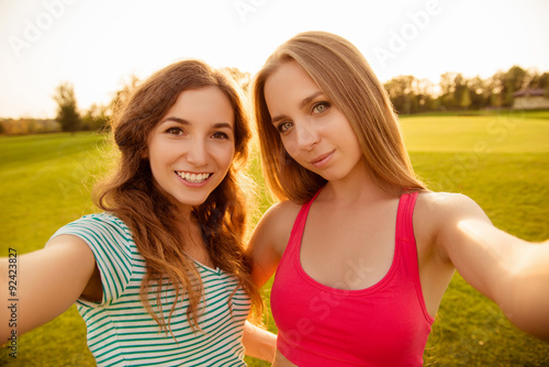 Two young sexy girls making selfie photo in the park