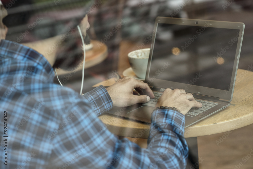 Young hipster man working on laptop in coffee shop Young hipster man working on laptop in coffee shop