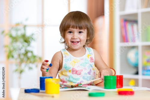 Happy child girl with hands painted color paints