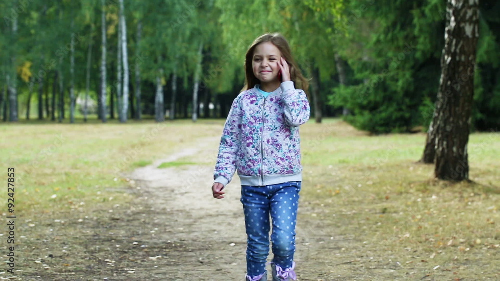 cute little girl is in the park and talking on the phone cute little girl is in the park and talking on the phone