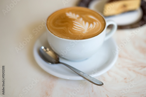 Cappuchino or latte coffe in a white cup on with a cake