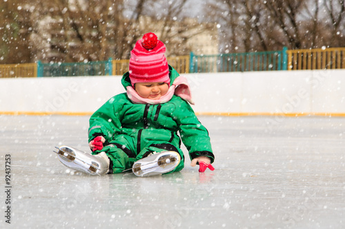 cute little girl sitting on ice with skates