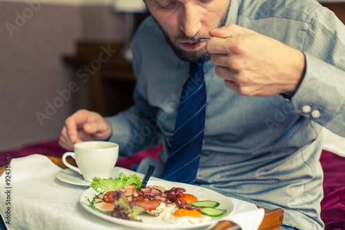Businessman eating breakfast at home hotel. Indoor photo.