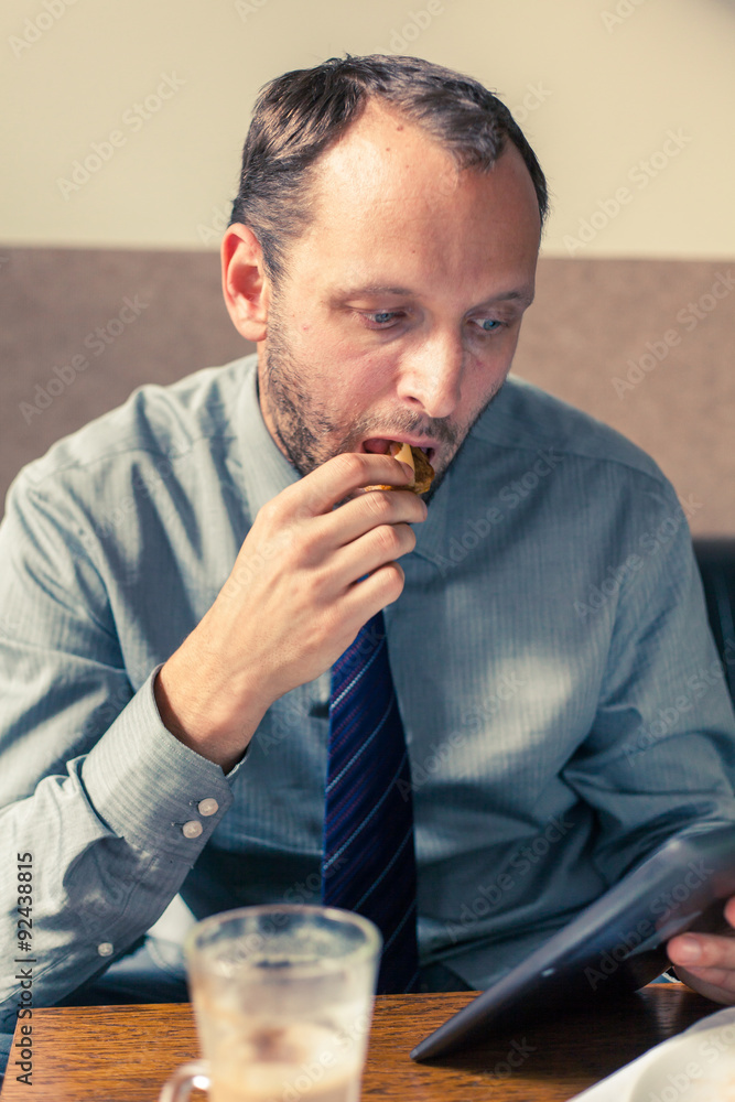 Businessman working on tablet pc during breakfast at home/hotel.