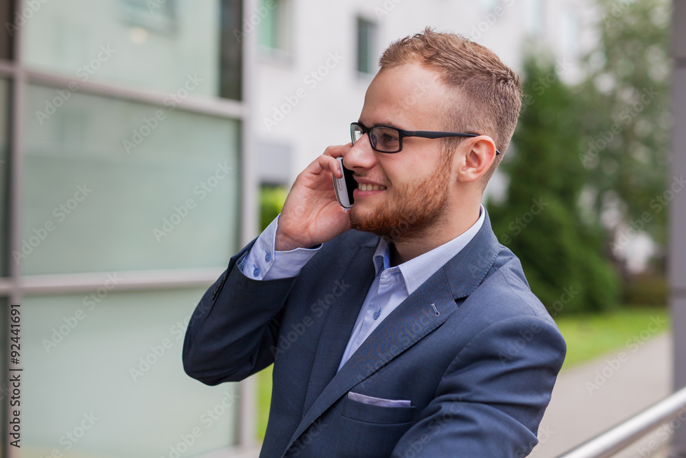 Caucasian businessman outside office using mobile phone on an office terrace. Caucasian businessman outside office using mobile phone on an office terrace.