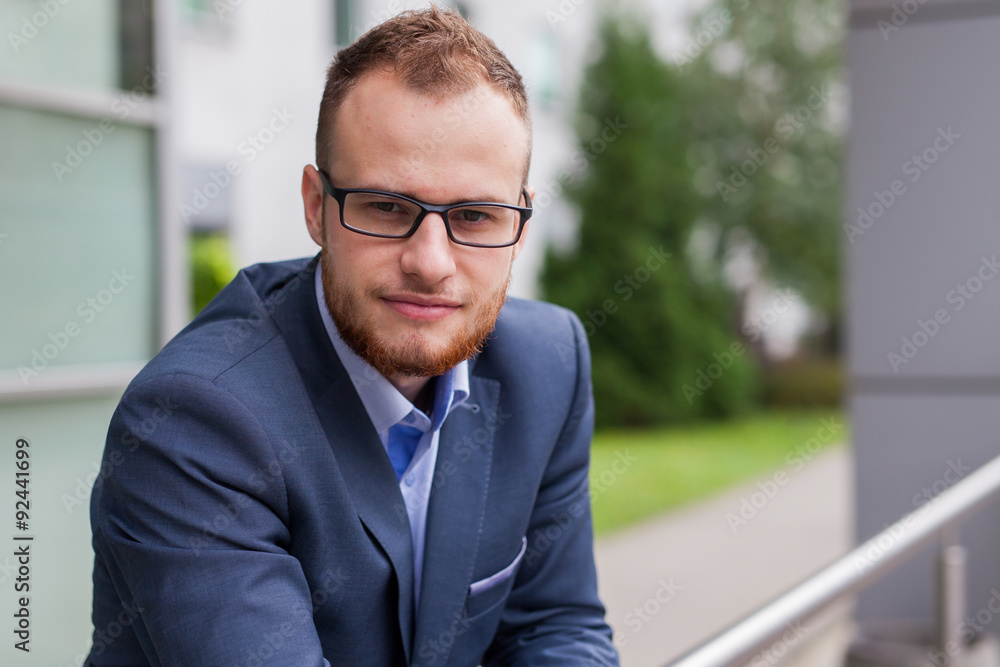 Portrait of young businessman with beard standing in front of office bulding. Portrait of young businessman with beard standing in front of office bulding.