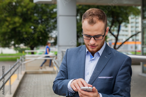 Caucasian businessman outside office using mobile phone on an office terrace.