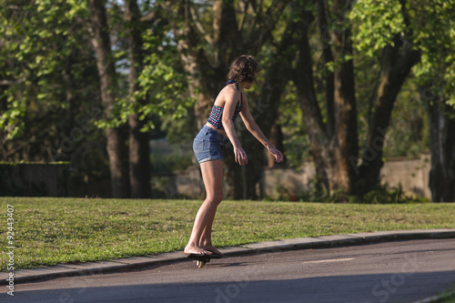 Girl riding snake skate board afternoon home driveway.