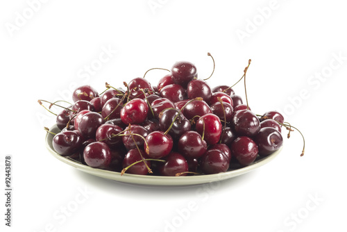 Ripe cherry on a green ceramic plate isolated on white