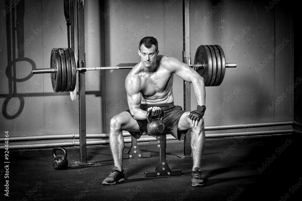 Man sitting and holding a kettlebell - crossfit Man sitting and holding a kettlebell - crossfit