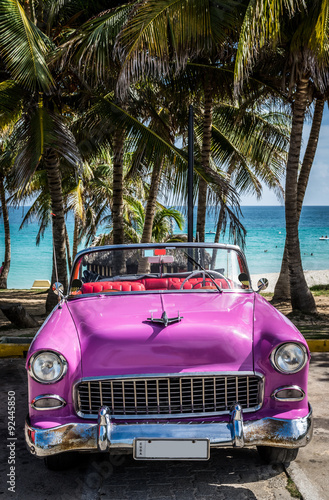Pinker Oldtimer parkt am Strand in Kuba